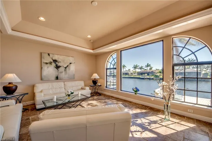 Living area with a raised ceiling, a water view, a wealth of natural light, and stone tile flooring