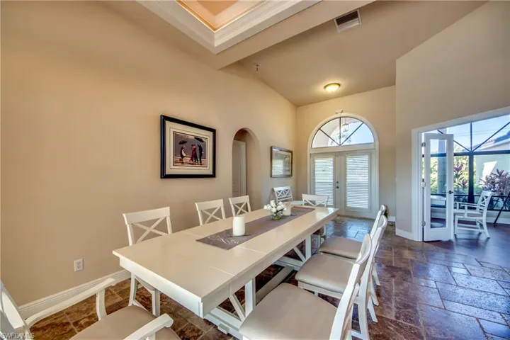 Dining room with arched walkways, visible vents, baseboards, and stone tile flooring