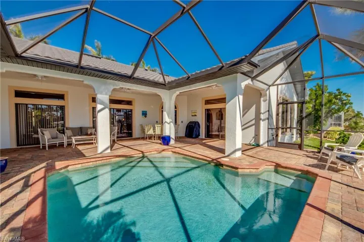 Outdoor pool with glass enclosure, outdoor lounge area, a ceiling fan, and a patio area