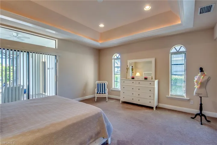 Carpeted bedroom featuring a tray ceiling, recessed lighting, baseboards, and visible vents