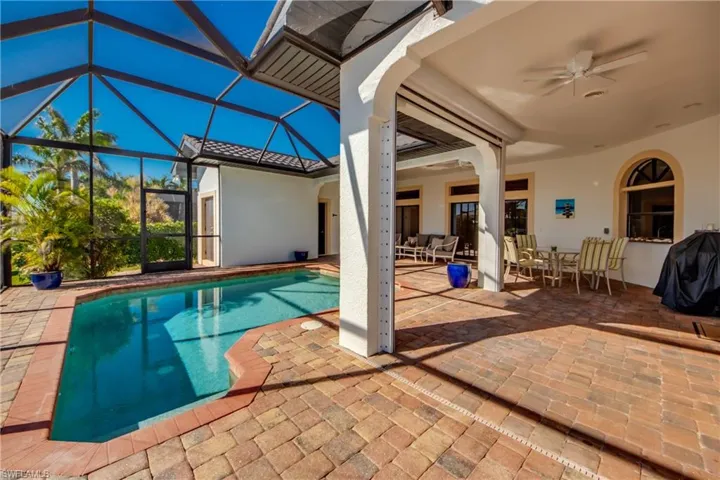 Outdoor pool featuring glass enclosure, outdoor dining area, ceiling fan, and a patio area
