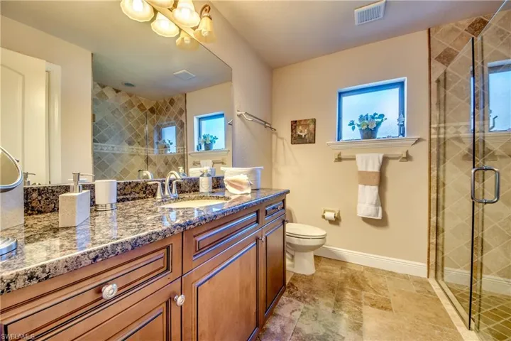 Full bathroom with toilet, baseboards, visible vents, and a stall shower