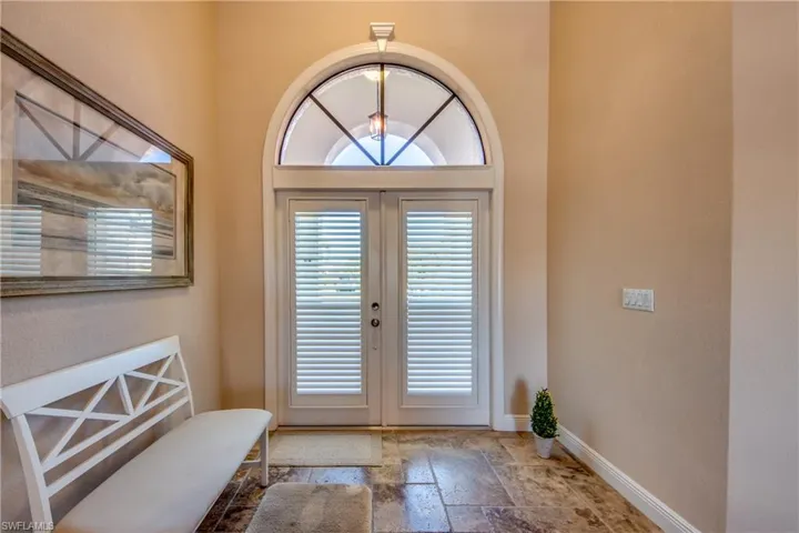 Entrance foyer with french doors, baseboards, and stone tile flooring