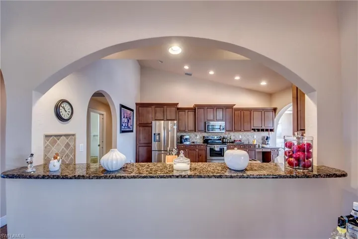 Kitchen featuring backsplash, a peninsula, stainless steel appliances, and dark stone counters