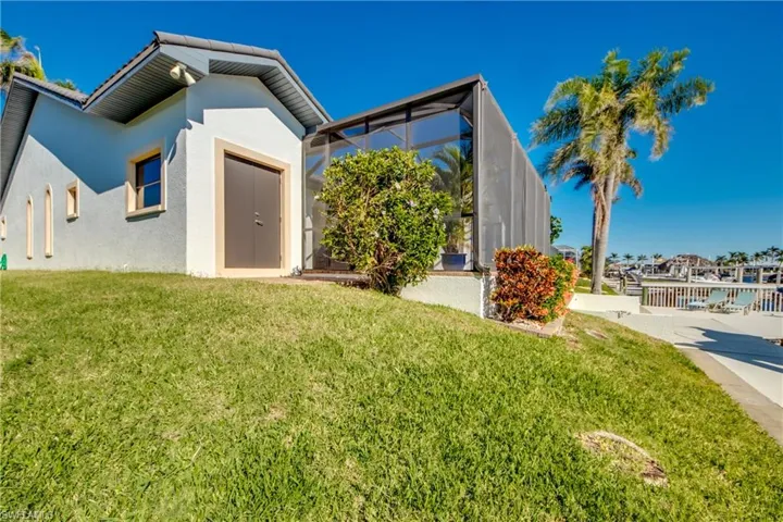 View of front of property with glass enclosure, a front lawn, and stucco siding