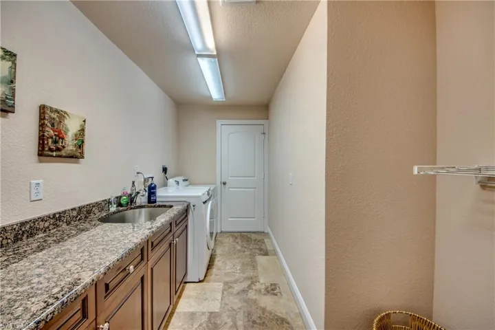 Washroom with baseboards, cabinet space, a sink, a textured ceiling, and washer and dryer