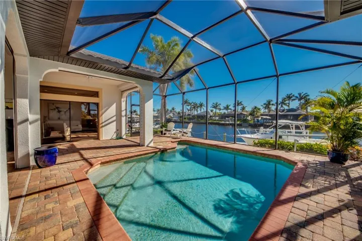 Pool featuring glass enclosure, a water view, a dock, and a patio area