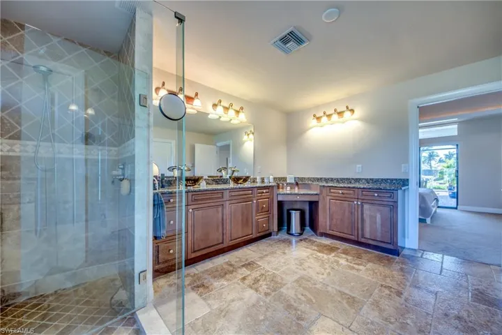 Full bath with vanity, stone tile floors, visible vents, and a stall shower