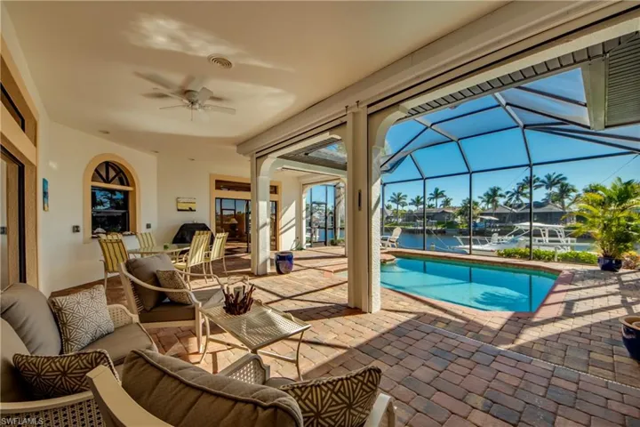 Outdoor pool featuring glass enclosure, a patio, ceiling fan, and outdoor lounge area