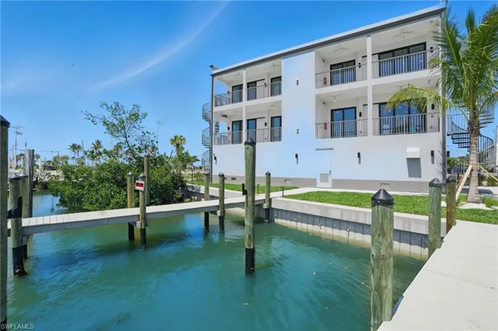 Waterfront multi-story structure featuring private balconies, spiral exterior staircase, and a private dock with direct water access - Virtually Edited Image