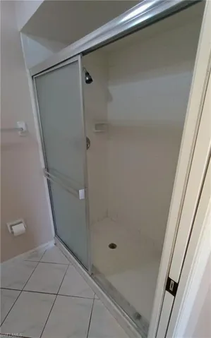 Full bathroom featuring a shower stall and tile patterned floors