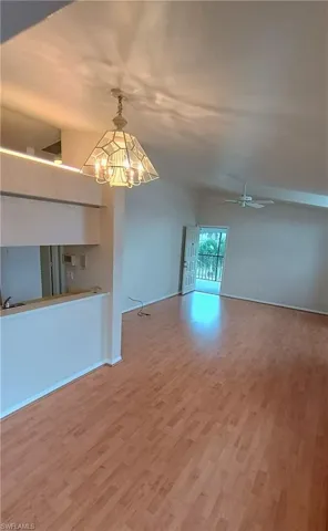 Unfurnished living room featuring wood finished floors, a chandelier, and a ceiling fan