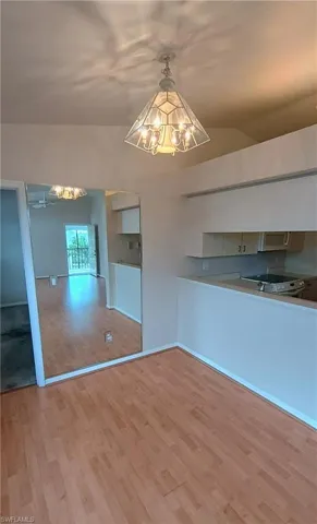 Unfurnished dining area with a chandelier, wood finished floors, and lofted ceiling