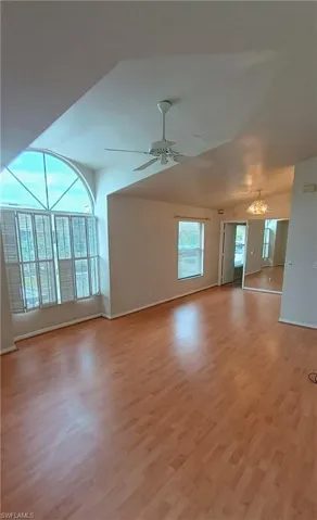 Unfurnished living room featuring light wood-type flooring, a ceiling fan, and a chandelier