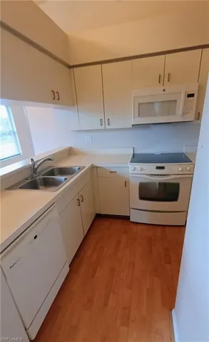 Kitchen featuring white appliances, light wood finished floors, light countertops, and white cabinets