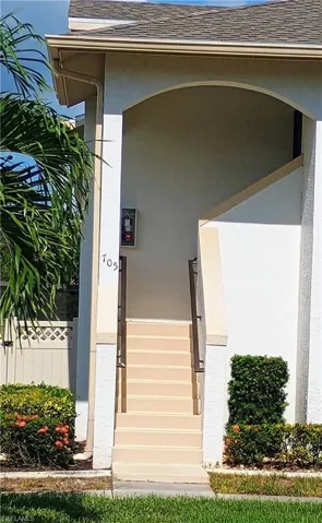 Doorway to property featuring stucco siding and roof with shingles
