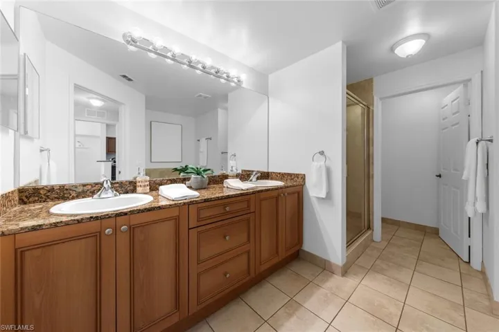 Bathroom with tile patterned floors, vanity, and a shower with shower door