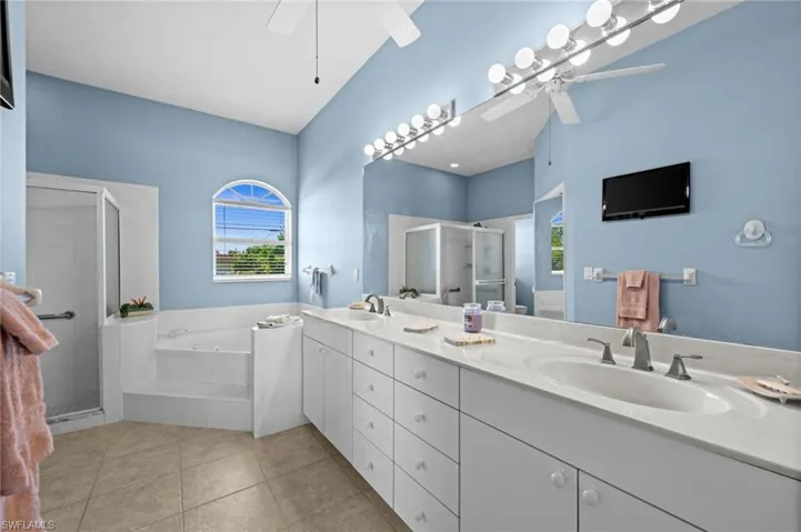 The en suite features natural light, a double vanity, a shower stall with safety bars, and a Jacuzzi tub. There's so much cabinetry and counter space.