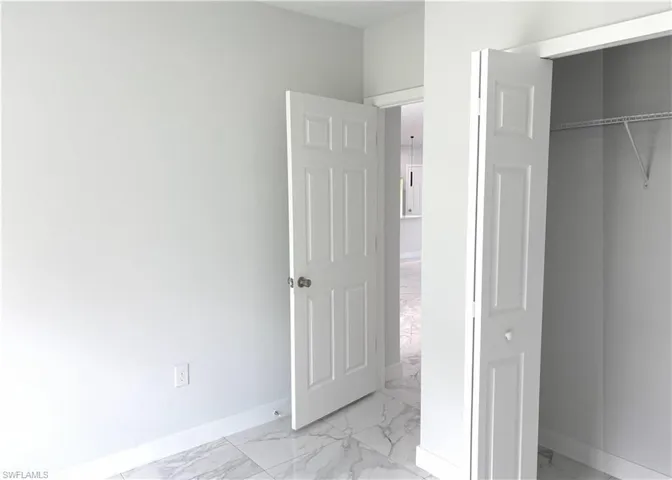 Unfurnished bedroom featuring light marble finish floors and a closet