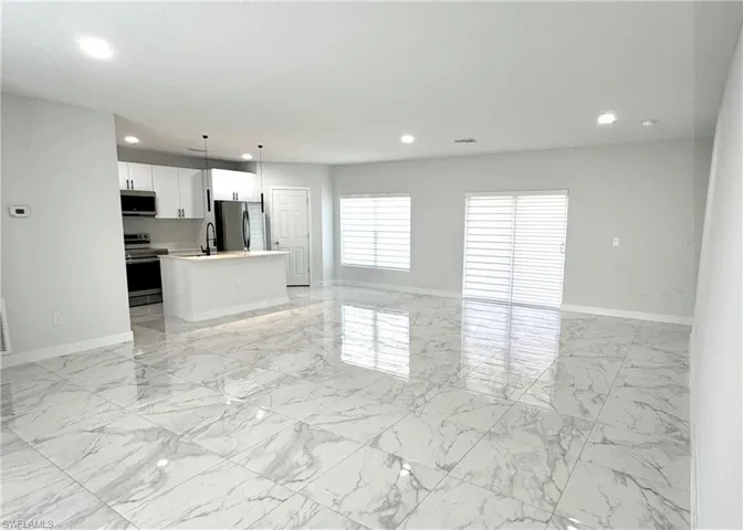 Unfurnished living room featuring light marble finish flooring and recessed lighting