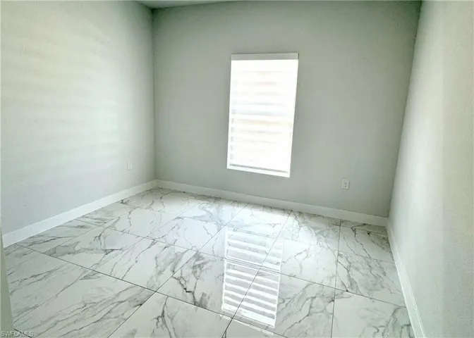 Empty room featuring light marble finish floors and baseboards