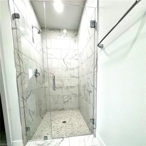 Full bathroom featuring a marble finish shower and marble look tile flooring