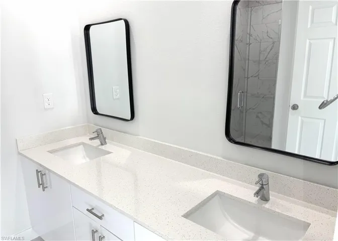Full bathroom with double vanity and a marble finish shower