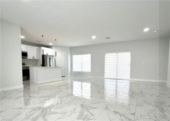 Unfurnished living room featuring light marble finish floors and recessed lighting