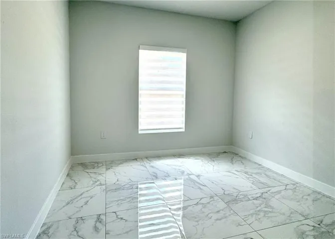 Empty room featuring light marble finish flooring and baseboards