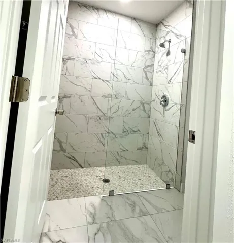 Bathroom with walk in shower and marble finish floors