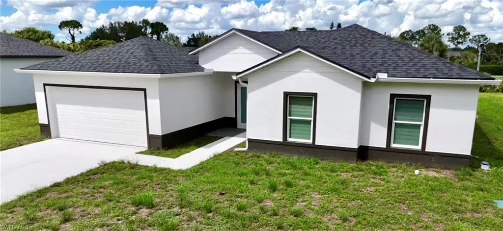 Ranch-style home with an attached garage, a front yard, and stucco siding