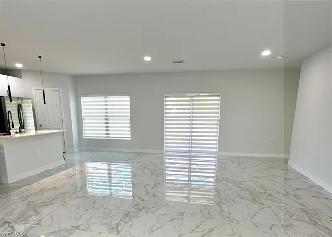 Unfurnished living room featuring light marble finish flooring and recessed lighting