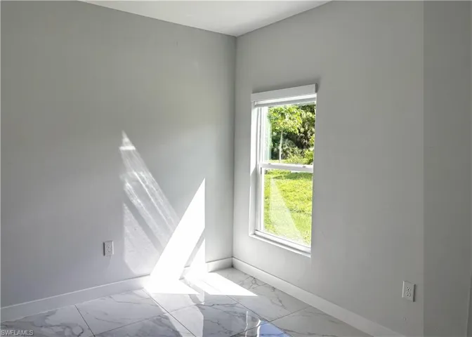 Spare room featuring baseboards and marble look tile flooring