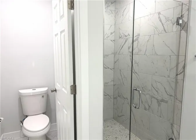 Full bath featuring a marble finish shower and toilet