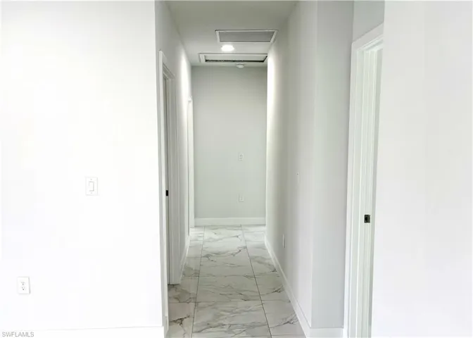 Hallway with attic access and light marble finish flooring