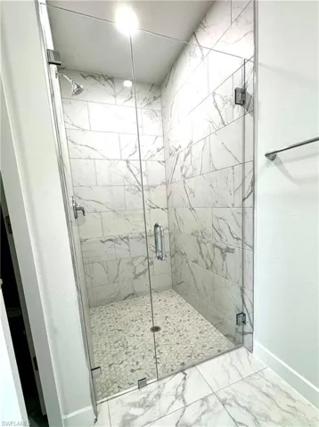 Bathroom with light marble finish floors and a marble finish shower