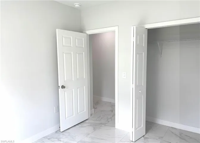 Unfurnished bedroom with light marble finish floors and a closet