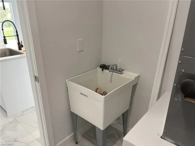 Washroom featuring light marble finish floors and a textured wall