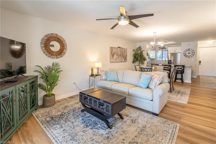 Living room with light wood-type flooring, ceiling fan, and a chandelier