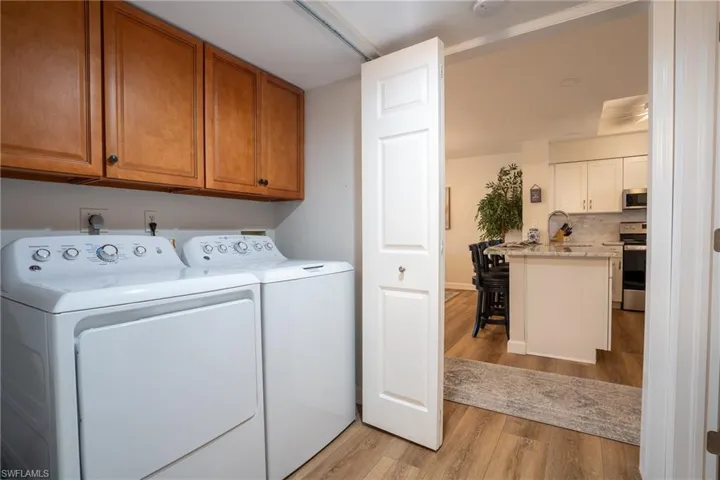 Washroom with light wood-style flooring, separate washer and dryer, and cabinet space