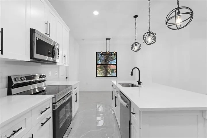 Kitchen featuring white cabinets, appliances with stainless steel finishes, and pendant lighting