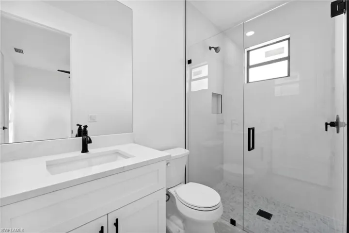 Bathroom featuring vanity, a shower with shower door, and toilet