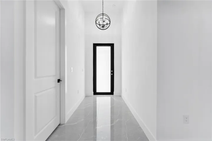 Corridor featuring an inviting chandelier