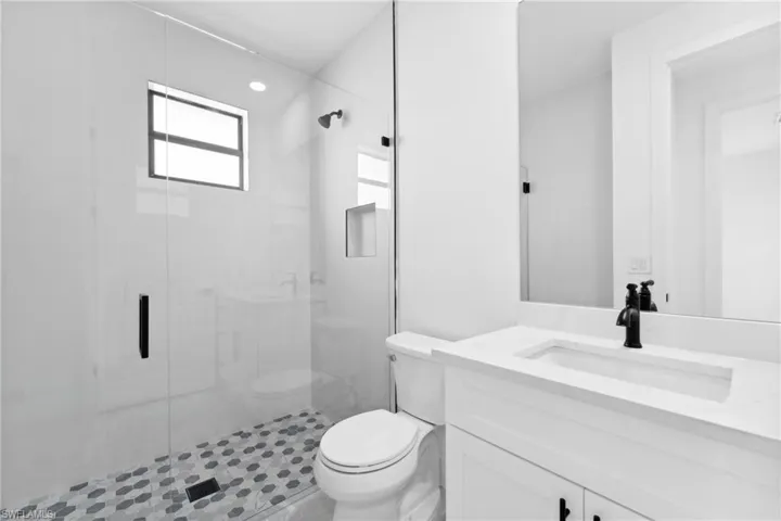 Bathroom featuring tile patterned flooring, vanity, a shower with shower door, and toilet