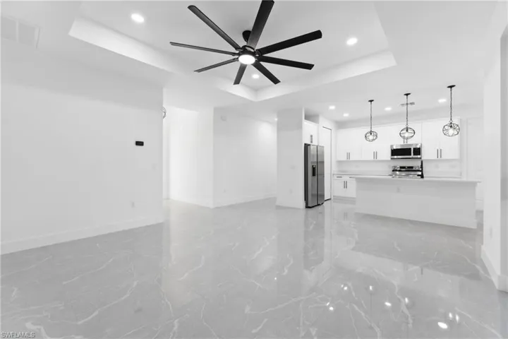Unfurnished living room featuring a tray ceiling and ceiling fan