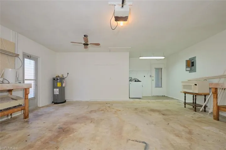 Garage with ceiling fan, electric water heater, electric panel, washer / dryer, and a garage door opener