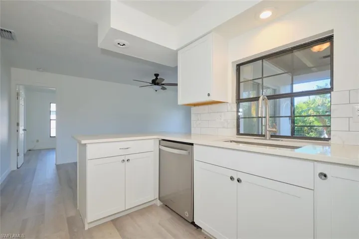 Kitchen featuring dishwasher, a healthy amount of sunlight, kitchen peninsula, and white cabinetry