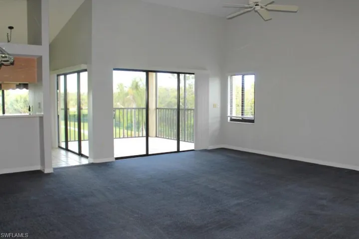 Unfurnished living room with high vaulted ceiling, carpet flooring, healthy amount of natural light, and baseboards