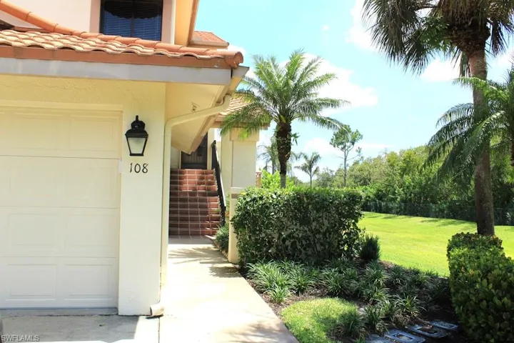 Doorway to property with a garage, stucco siding, and a lawn