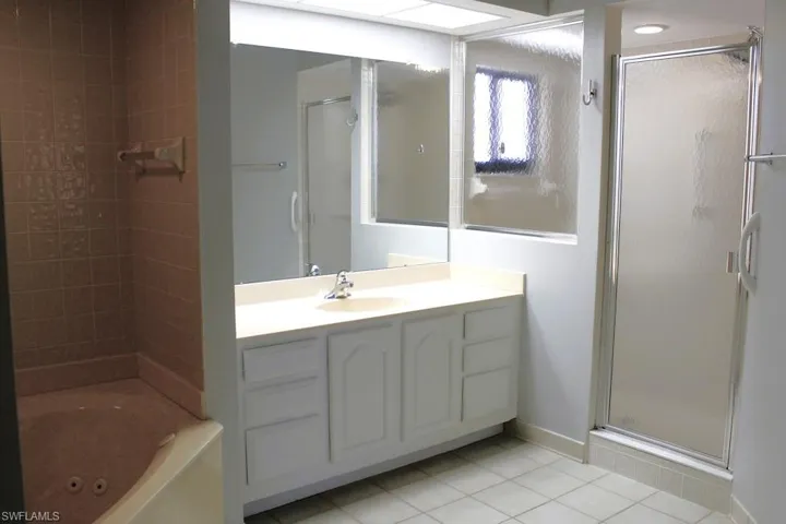 Full bath featuring a stall shower, light tile patterned flooring, vanity, and a jetted tub